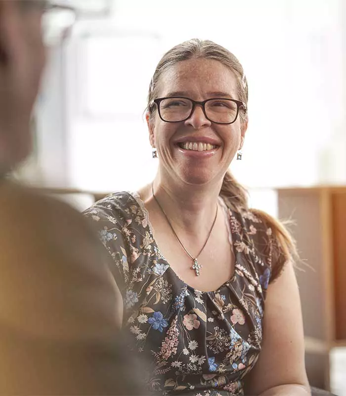 Porträt einer hilfsbereiten Mitarbeiterin die lächelnden in einem Gespräch vertieft ist.